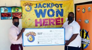 Julian King (left), Marketing Manager, The Barbados Lottery presents Mega 6 Jackpot winner Nicholas Archer with his winning cheque for $392,500 at The Barbados Lottery Retail Agent located at the One Boscobelle Complex in St. Peter.