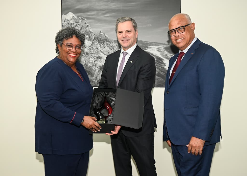 Harry Culham presents the Flame Award to Prime Minister Mottley while CEO Mark St. Hill looks on